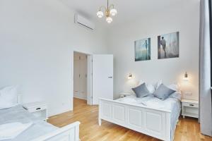 a white bedroom with two beds and a mirror at WISUS 24 in Świnoujście