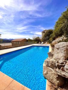 a large blue swimming pool with a stone wall at Appartement 2 chambres à Lama avec Piscine in Lama
