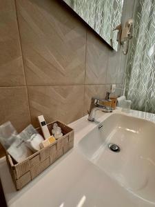 un lavandino in bagno con un cesto di asciugamani e uno specchio di M.Mansion a San Giovanni Rotondo