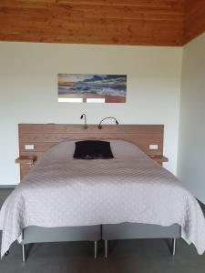 Schlafzimmer mit einem weißen Bett mit einem Kopfteil aus Holz in der Unterkunft BenB Zuidoord in Zuidland