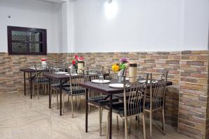 uma sala de jantar com mesas e cadeiras e uma parede de tijolos em Lava Hotel Aashiyana em Lava