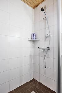 um chuveiro numa casa de banho em azulejos brancos em Rauhallinen kolmio omalla saunalla Tampereen keskustassa em Tampere