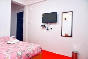 um quarto com uma cama e uma televisão na parede em Lava Hotel Aashiyana em Lava