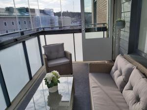 a balcony with a couch and a chair and a glass table at Rauhallinen kolmio omalla saunalla Tampereen keskustassa in Tampere