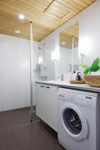 a washing machine in a bathroom with a sink at Rauhallinen kolmio omalla saunalla Tampereen keskustassa in Tampere