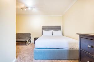 a bedroom with a white bed and a chair at Austin David Apartments - Hendon Pad in Hendon