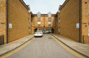 a white car parked in a tunnel between two brick buildings at Austin David Apartments - Hendon Pad in Hendon