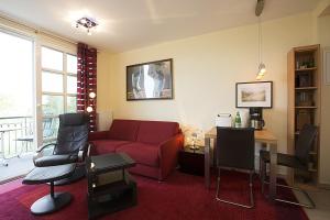 ein Wohnzimmer mit einem roten Sofa und Stühlen in der Unterkunft Residenz am Balmer See - BS 51 mit Wellnessbereich in Balm