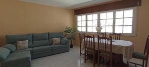 ein Wohnzimmer mit einem blauen Sofa und einem Tisch in der Unterkunft EnBurela Lujo A Pie de Playa in Burela