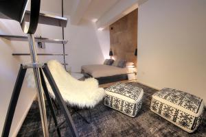 a room with a bed and a chair and ottoman at Urban Central Suites in Cagliari