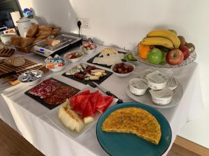 einen Tisch mit Teller mit Lebensmitteln und Schalen mit Früchten in der Unterkunft Balcón de Gijón Apartamentos Boutique in Gijón