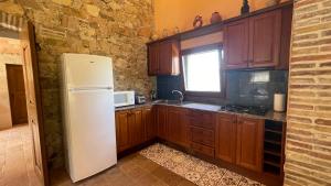 a kitchen with wooden cabinets and a white refrigerator at AMAZING Typical House with Swimming Pool in Sant Feliu de Guíxols