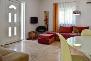 ein Wohnzimmer mit einem roten Sofa und einem Tisch in der Unterkunft Μονοκατοικία δίπλα στην Θάλασσα in Salamís