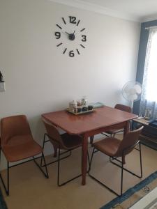 a dining room table with chairs and a clock on the wall at Telperio - Guest suite max 4 Guests in Bunbury