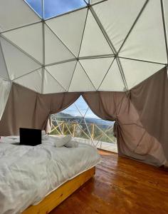 ein Bett in einem Zelt mit einem Laptop darauf in der Unterkunft Bali Glamping in Ambrolauri