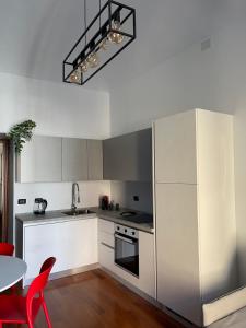 Margarita Apartment Porta Susa Torino في تورينو: مطبخ مع دواليب بيضاء وطاولة مع كراسي حمراء