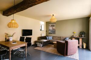 uma sala de estar com um sofá e uma mesa em Hoeve de Reetjens - La Porcherie em Bilzen