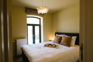 um quarto com uma grande cama branca e uma janela em Hoeve de Reetjens - La Porcherie em Bilzen