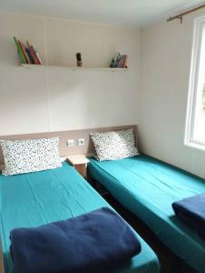 2 camas en una habitación con sábanas azules en Mobil-home tout confort climatisé 6 personnes proche Europa Park, route des vins, Alsace en Boofzheim