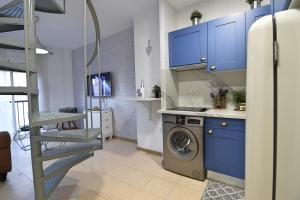 Apartamento Inespe في مالقة: مطبخ مع دواليب زرقاء وغسالة ملابس