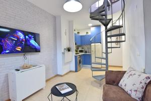 Apartamento Inespe في مالقة: غرفة معيشة مع أريكة ودرج حلزوني