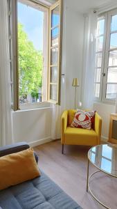 a living room with a yellow chair and a window at Dastro Logis in Saint-Rémy-de-Provence