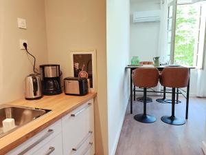 a kitchen with a sink and a counter with two chairs at Dastro Logis in Saint-Rémy-de-Provence