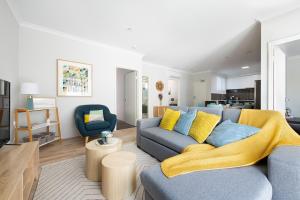 een woonkamer met een blauwe bank en een gele deken bij Bright Trendy 2bdrm Apt - Walk to River & Shops in Perth