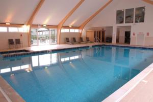 a large swimming pool with blue water in a building at Skylark sleeps 8 private Hot Tub & Dogs welcome Nr Padstow, Resort Pool Bar & Watersports in Saint Columb Major