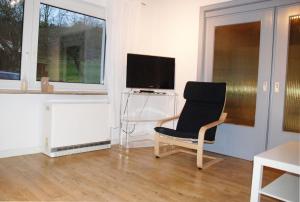 a living room with a chair and a television at Ferienwohnung Schmäing, Haiger/Westerwald / Rothaarsteig in Haiger