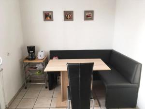 a table with a black couch and a table and chairs at Ferienwohnung Schmäing, Haiger/Westerwald / Rothaarsteig in Haiger