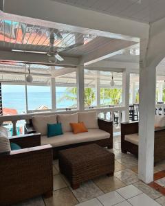 un porche cubierto con sofá y sillas en Los Delfines Hotel & Dive Center, en Little Corn Island