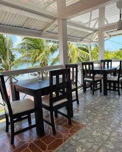 un patio con mesas, sillas y palmeras en Los Delfines Hotel & Dive Center, en Little Corn Island