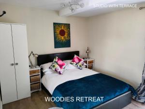 a bedroom with a bed with a blue blanket and pink pillows at Woodies in Peasmarsh