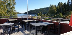 a deck with tables and chairs and a view of a river at Skutskepparn Kuststation in Nordingrå