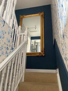 a stairway with a mirror and blue walls at Summer Cottage in Kinsale in Kinsale