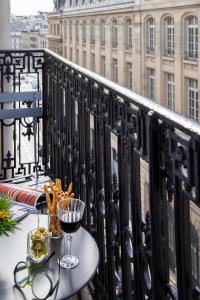 a table on a balcony with a glass of wine at Philéas Lazare & Spa in Paris