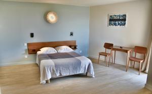 een slaapkamer met een bed en een tafel met stoelen bij hôtel Le Grand Large in Gruissan