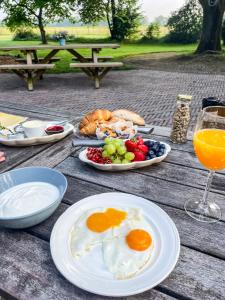 een houten tafel met borden en een glas sinaasappelsap bij De Loeghoeve in Anderen