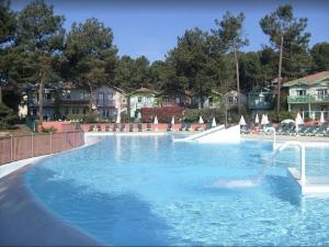 duży basen z błękitną wodą w ośrodku wypoczynkowym w obiekcie Maison NAUCALA proche de la piscine w mieście Lacanau