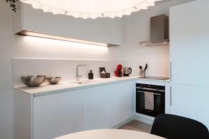 a white kitchen with a sink and a counter at La Palma 1 by Quokka 360 - modern panoramic lake view flat in Montagnola