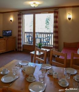 een houten tafel met borden en kopjes erop bij travelski home premium - Résidence Les Alpages de Val Cenis 4 in Les Champs