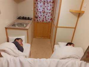 zwei Männer liegen in Betten in einem Zimmer in der Unterkunft Véritable roulotte à la campagne in Bassillon-Vauzé