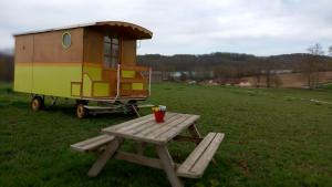 ein Spielhaus und ein Picknicktisch auf einem Feld in der Unterkunft Véritable roulotte à la campagne in Bassillon-Vauzé