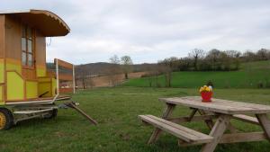 einen Picknicktisch und einen Anhänger auf einem Feld in der Unterkunft Véritable roulotte à la campagne in Bassillon-Vauzé