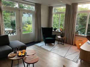 een woonkamer met een bank, stoelen en ramen bij De Lijster in Bergen