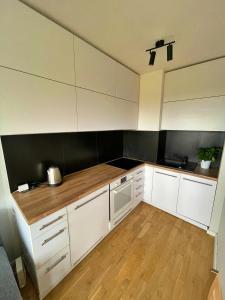 a kitchen with white cabinets and a wooden floor at Szucha 27 - Royal Łazienki Flat in Warsaw