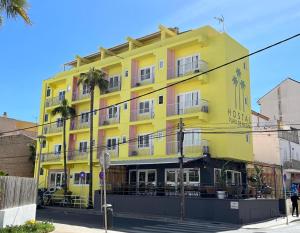 un edificio giallo con palme di fronte di Hostal Playa de Palma a Playa de Palma