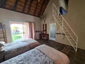 a bedroom with two beds and a spiral staircase at Tamboti Farm Accommodation in Tsumeb