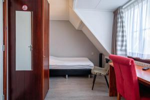 een kleine kamer met een bed en een bureau met een stoel bij Hotel Brasserie Rebecca in De Waal